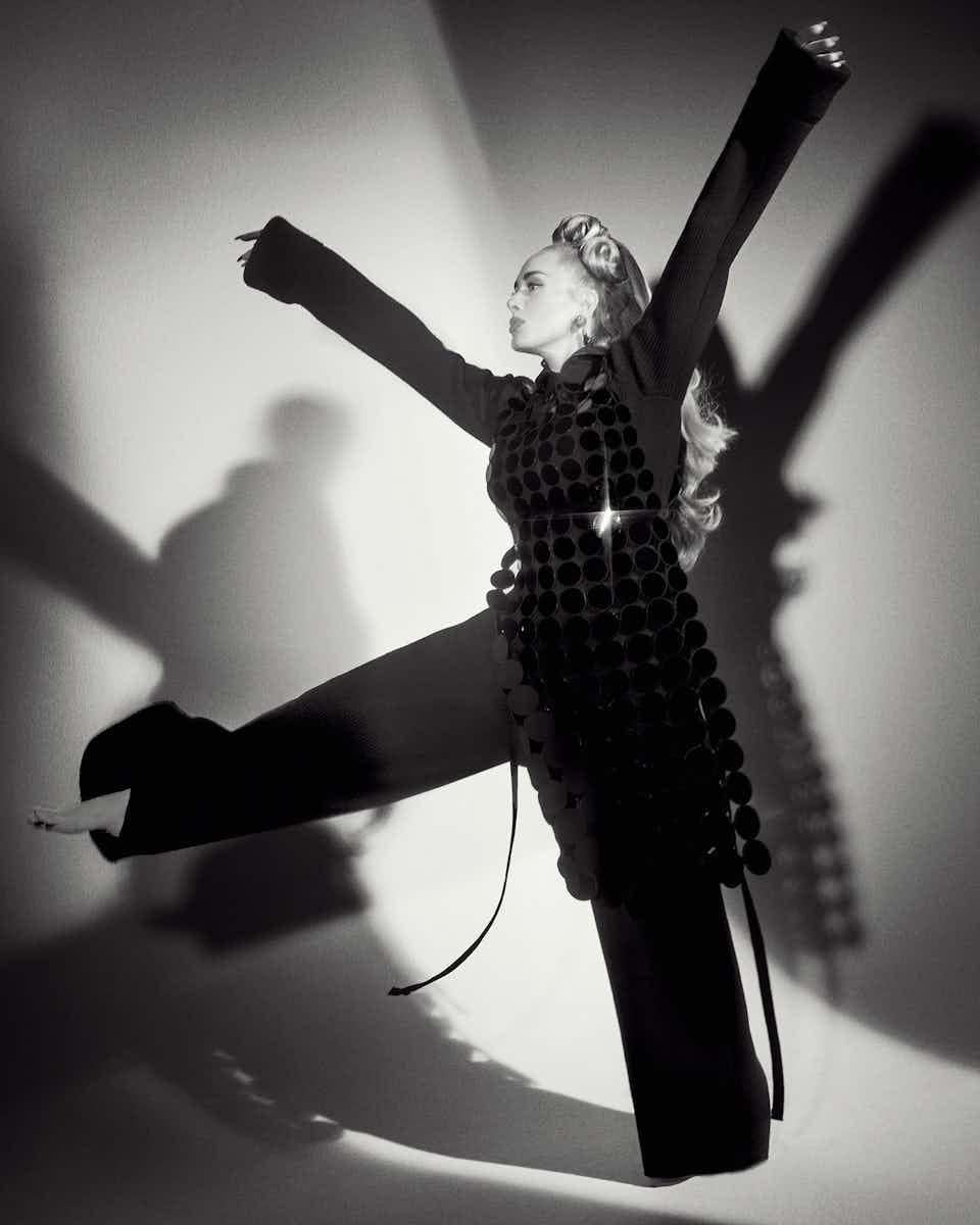 Adele wearing a black dress, trousers and jumper which are all Marc Jacobs. The photo is in black and white, shot by Charlotte Wales for The Face magazine.